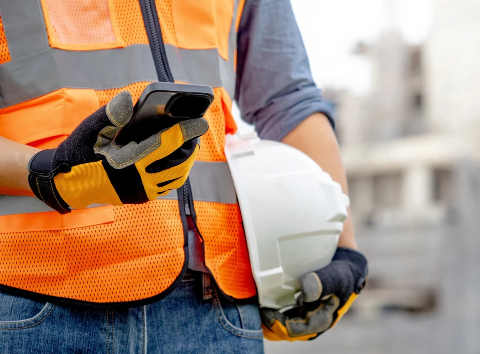 Jeune homme souriant prenant un selfie, faisant un signe de victoire avec les doigts, dans un espace int&eacute;rieur moderne avec mur de briques apparentes