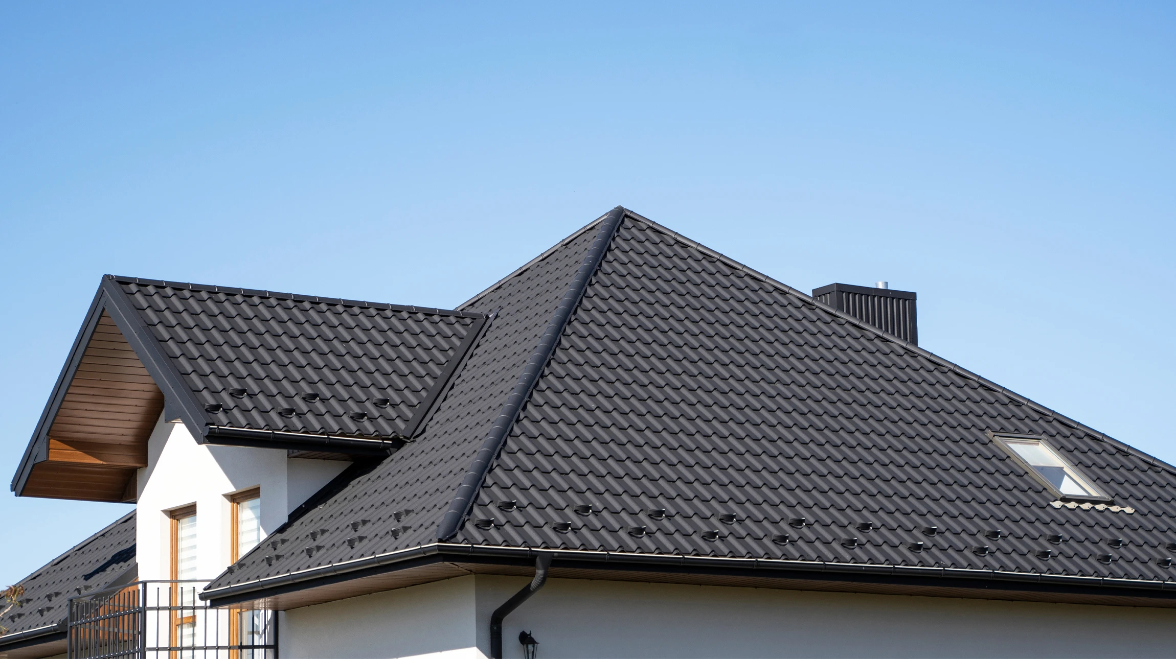 Ouvrier en train d'installer des bardeaux d'asphalte sur une toiture résidentielle, travaillant à genoux sur la pente du toit